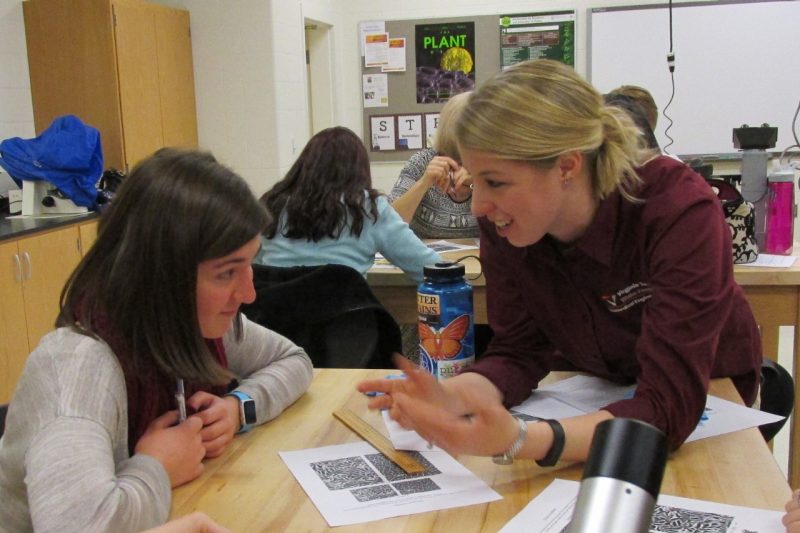 A doctoral student talks with a high school science student about research