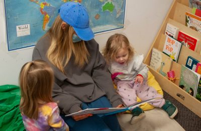 A teacher and two children read together