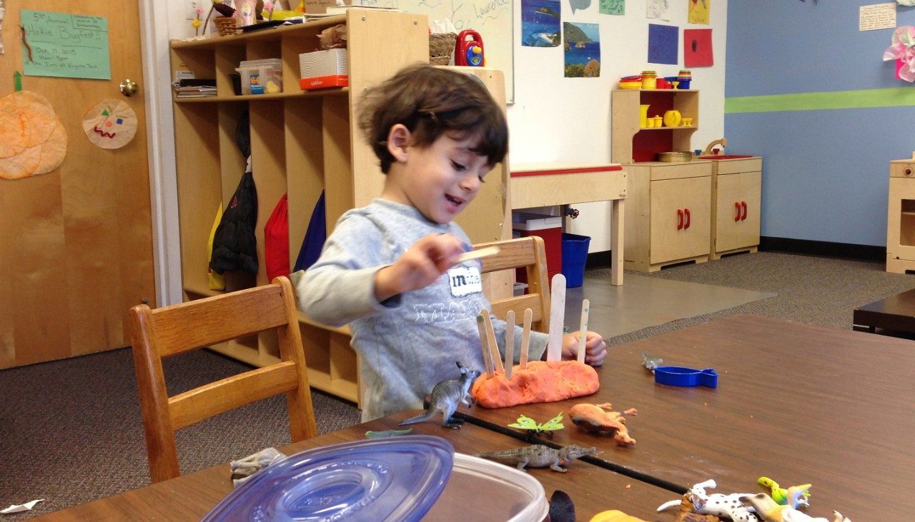 a boy playing with modeling clay at Little Hokie Hangout child care center