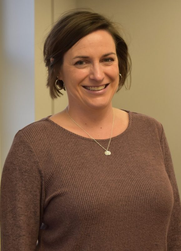 Amanda Pettigrew smiling in room 120 of the Graduate Life Center