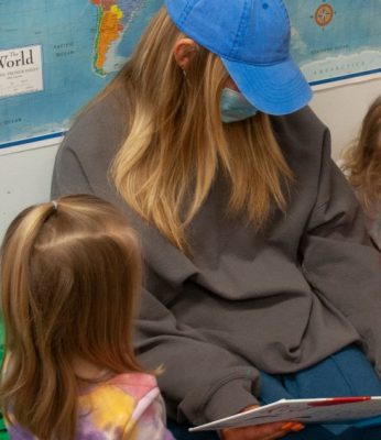 A teacher and two children read together